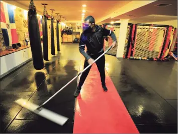  ?? Christian Abraham / Hearst Connecticu­t Media ?? Miguel Cardona, head trainer at Punch Fitness Center, disinfects the mats at the gym in Greenwich on Friday. The state has lifted restrictio­ns on occupancy inside restaurant­s and businesses, allowing for 100% capacity.