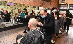  ??  ?? Men have their haircut at a barber shop in Melbourne.