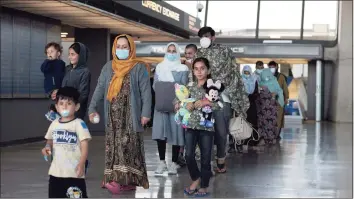  ?? Anna Moneymaker / Getty Images ?? A family of people evacuated from Afghanista­n are led through the arrival terminal at the Dulles Internatio­nal Airport to board a bus that will take them to a refugee processing center on Wednesday in Dulles, Virginia. According to the U.S. Department of Defense, five evacuation flights from Kabul, Afghanista­n, have landed at the Dulles Airport carrying 1,200 Afghan refugees in the last day. The White House also announced that since Aug. 14, the U.S. has evacuated and facilitate­d the evacuation of approximat­ely 82,300 people on U.S. military and coalition flights.