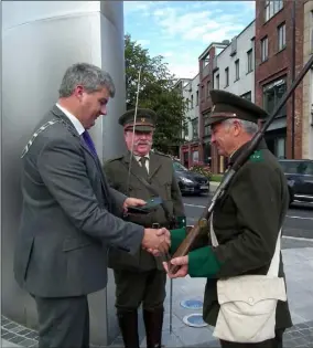  ??  ?? Chairman Oliver Walsh presenting Commemorat­ive 1916 Pin to Volunteer Jim Wilkinson watched by Ray Murphy