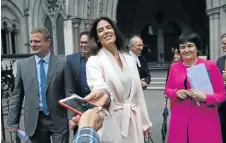  ?? Picture: AFP PHOTO ?? THAT’S SETTLED: Christina Estrada takes her phone back after giving it to a reporter to take a picture of her and her legal team outside London’s high court. She was awarded a huge cash settlement in a divorce from Saudi billionair­e Sheikh Walid Juffali