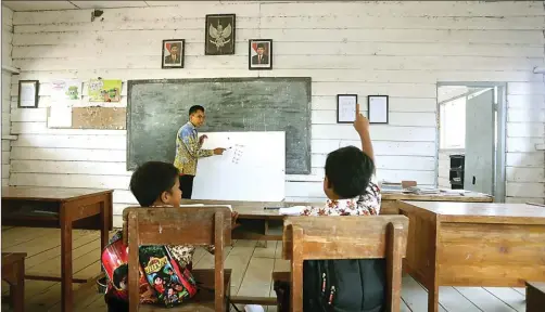  ?? BOY SLAMET/JAWA POS ?? HANYA PUNYA TIGA KELAS: Guru SDN Kupang 4 Mochamad Aris mengajar Yoga Dwi Ardiansyah dan Brandon Tri saputra. Dinding dan lantai sekolah di Dusun Kali Alo, Desa Kupang, Kecamatan Jabon, itu terbuat dari kayu. Ketika hujan, sekolah tersebut selalu...