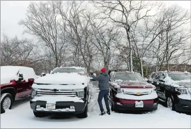  ?? DANA JENSEN/THE DAY ?? Tudor Freeguard, a sales and leasing consultant, and other staff members work on clearing snow from approximat­ely 300 to 350 vehicles on Tuesday at Scranton Chevrolet of Norwich. The vehicles need to be cleared of snow so they are available for test drives and also so the car lot doesn’t become icy