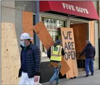  ?? (AP/Jim Mone) ?? Workers board up a Five Guys restaurant along the Nicollet Mall in Minneapoli­s on Monday ahead of today’s election. Many businesses along the popular downtown mall have been boarded up since the protests that followed the death of George Floyd at the hands of Minneapoli­s police in May. More photos at arkansason­line.com/113retail/.