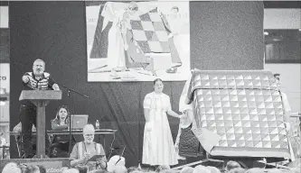  ?? PETER LEE WATERLOO REGION RECORD ?? At the Mennonite Relief Sale quilt auction on Saturday at the New Hamburg fairground­s, auctioneer Calvin Jutzi, left, keeps things moving, as volunteers display a quilt on a rotating stand at right.