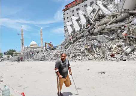  ?? File/AFP ?? A disabled Palestinia­n man walks past the rubble of buildings destroyed by Israeli airstrikes in Gaza City in May. Billions are needed to rebuild the city.