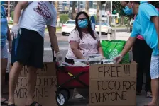  ?? JON GAMBRELL — THE ASSOCIATED PRESS ?? Feby Cachero Baguisa Dela Pena of Laguna, Philippine­s, hands out free food to those who need it in Dubai, United Arab Emirates on June 3.