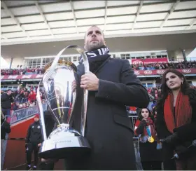  ?? Chris Young / Canadian Press ?? Former Toronto FC player Benoit Cheyrou carries the MLS championsh­ip trophy onto the field before the season opener against the Columbus Crew.