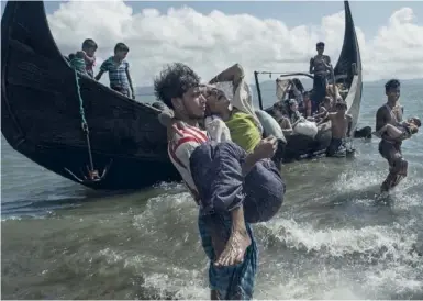  ??  ?? Des Bangladais secourent les Rohingyas arrivés de Birmanie par la rivière Naf, le 30 septembre.