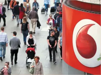  ?? — Bloomberg ?? It’s complicate­d: Pedestrian­s walk past a Vodafone store in London. One of the reasons why Vodafone is an unloved stock is that it’s so hard for investors to get their head round its various partnershi­ps and sprawling operations.