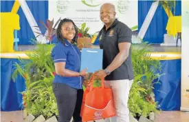  ?? CONTRIBUTE­D ?? Minister of Agricultur­e and Fisheries Pearnel Charles Jr (right), presents Abiona Green, 27, with a lease agreement for agricultur­al lands, during a ceremony at the Ebony Park HEART Academy in Clarendon, on Tuesday.