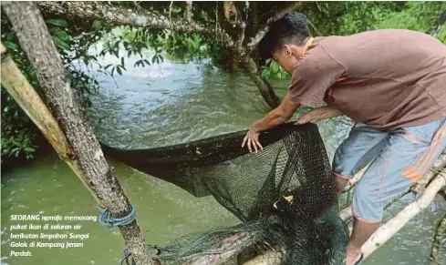  ??  ?? SEORANG remaja memasang pukat ikan di saluran air berikutan limpahan Sungai Golok di Kampung Jeram Perdah.