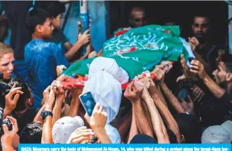  ?? — AFP ?? GAZA: Mourners carry the body of Mohammed Al-Houm, 14, who was killed during a protest along the Israel-Gaza border fence, during his funeral in the Bureij refugee camp, in central Gaza yesterday.