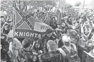  ?? ASSOCIATED PRESS ?? Members of the Ku Klux Klan are escorted by police past protesters during a rally in Charlottes­ville, Va., in July. Some white Southerner­s are again advocating for secession.