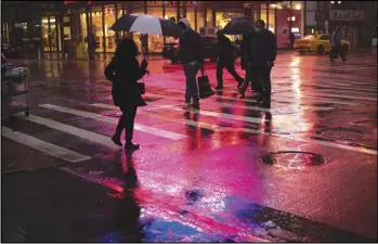  ?? ASSOCIATED PRESS ?? Shoppers walk in a rainstorm, Monday in New York.