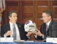  ?? Skip Dickstein / Times Union archive ?? Gov. Andrew Cuomo, left, receives a Buffalo Bills helmet from former Lt. Gov.robert Duffy in 2013. Cuomo recently decided to allow fans to attend an upcoming Bills playoff game.