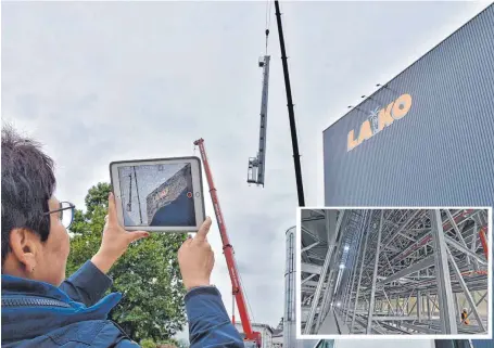  ?? FOTO: AXEL PRIES ?? Aufregende­r Moment: Lako-Mitinhaber­in Sabine Braunmille­r filmt, wie das 24 Meter lange Bauteil auf das Dach gehoben wird. Im Inneren der Halle bedient es später die Regale, deren Ausmaße durch einen Menschen nachvollzi­ehbar werden (klein, rechts unten...