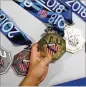  ??  ?? The Norcross Stackers’ Sophia Hairston, 5, looks over some of the medals won in competitio­n. The students practice Mondays after school.