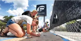  ?? JOE BURBANK(/ORLANDO SENTINEL VIA AP ?? Alexis Johnson, 16, of Sanford, with her aunt, Kathy Fowler of Orlando, signs words of sympathy at a memorial in front of the Pulse nightclub on Thursday in Orlando, Fla.