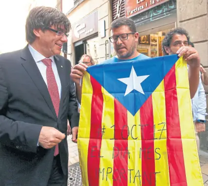  ??  ?? Puigdemont, junto a un catalán con la bandera regional y la fecha