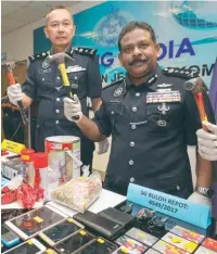  ??  ?? Thaiveegan and Federal CCID deputy (intelligen­ce and operations) Senior Asst Comm Mohd Sakri Arifin showing hammers used to threaten debtors and other items seized from the loan sharks.