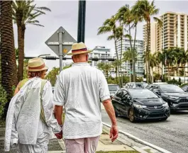  ?? ?? A couple walk along the sidewalk in Bal Harbour, Fla. A new law in Florida promotes affordable housing, but local officials hate it. The law, which lets developers bypass local zoning rules if they promise “workforce housing,” has stirred an uproar in affluent Bal Harbour and other places.