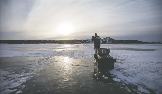  ?? LIAM RICHARDS ?? A Saskatoon firefighte­r hauls equipment to a tent, which is being used for under-ice dive training; on Blackstrap Lake.