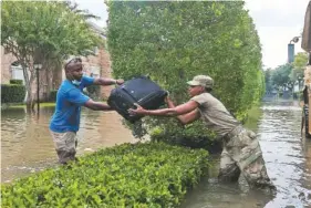  ?? BRYAN THOMAS/THE NEW YORK TIMES ?? Waiyaki Gichanga passes a bag of his belongings to Pfc. Eliska Dillon of the National Guard in Houston on Sept. 3.