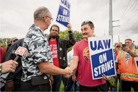  ?? Bill Pugliano/Getty Images ?? United Auto Workers President Shawn Fain greets UAW members as they strike the General Motors Lansing Delta Assembly Plant on in Lansing, Michigan on Friday. The UAW expanded their strike against General Motors and Ford, claiming there has not been substantia­l progress toward a fair contract agreement.