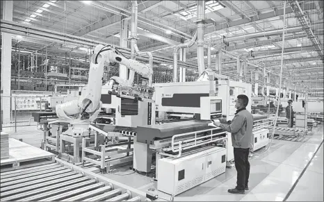  ?? ZHU HAIPENG / FOR CHINA DAILY ?? Top: A worker operates a robotic arm on a houseware production line at a digital workshop in Ganzhou, Jiangxi province, in February.