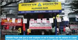  ??  ?? KOLKATA: People walk past as bank employees sit next to banners near the entrance of a closed bank during a strike in Kolkata yesterday. Two banking unions called the strike in response to the Indian government’s decision to merge ten public sector banks into four banks. —AFP