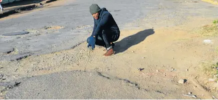  ?? Picture: ABONGILE SOLUNDWANA ?? TRAFFIC ALERT: The Rep reporter Bhongo Jacob surveys one of many potholes marring the road surfaces of Komani