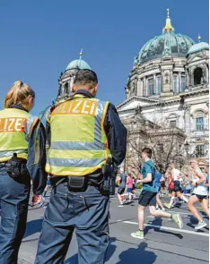  ?? Foto: Christophe Gateau, dpa ?? Polizisten sichern die Halbmarath­on Strecke in Berlin. Im Hintergrun­d der Berliner Dom.