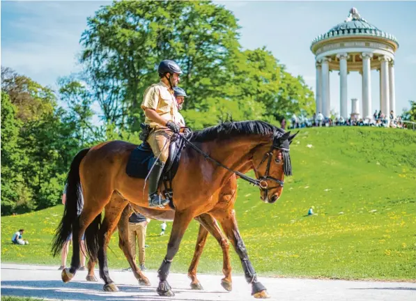  ?? Foto: Lino Mirgeler, dpa ?? Auf Streife im Englischen Garten in München: Beamte der polizeilic­hen Reiterstaf­fel. Im Hintergrun­d der Monopteros.