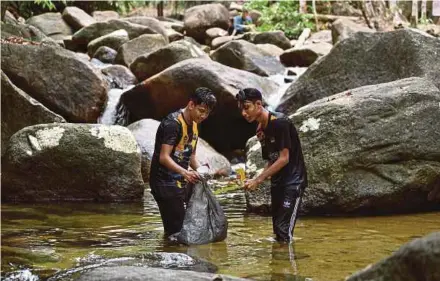  ?? BERNAMA PIC ?? Brothers Mohamad Shahmirul Aswad Sabaruddin (left), 24, and Muhammad Dahmin Izmar Aqif, 18, collecting rubbish at the Kledang Saiong Forest Eco Park waterfall, outside Ipoh, yesterday.
