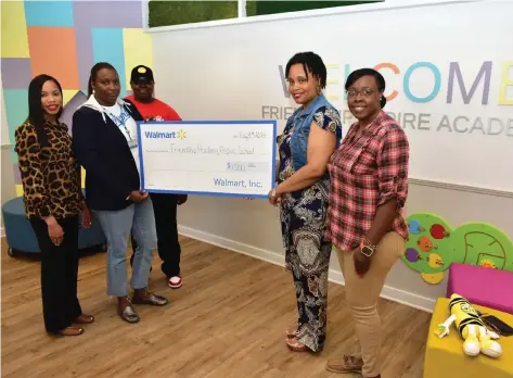  ?? (Pine Bluff Commercial/I.C. Murrell) ?? Friendship Aspire Academy Downtown Campus teachers accept a $1,000 check from Walmart in the school lobby on Thursday. Principal Ashley Williams (from left), Walmart store manager Essica Clifton, Walmart team leader Brittany Lowden, and teachers Melanie Madkin and Krystal Cosen celebrate the gift.