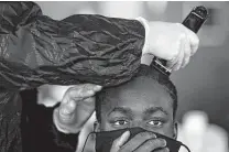  ??  ?? A trainee at JBSA-Lackland gets a haircut on the first day of basic training. Because of the pandemic, barbers come to the atriums of recruits’ dorms, as do personal items.