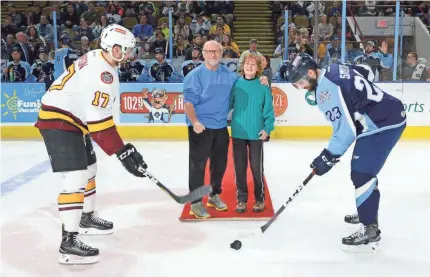  ?? DAVE KALLMANN / MILWAUKEE JOURNAL SENTINEL ?? Steve and Diane Homfeldt drop the ceremonial first pucks for Paul Thompson (left) of the Chicago Wolves and Trevor Smith of the Milwaukee Admirals before Tuesday’s game at the UW-Milwaukee Panther Arena. The Homfeldts, married in 1983, marked their...