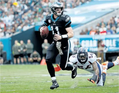  ?? JOE ROBBINS/GETTY IMAGES ?? Philadelph­ia Eagles’ quarterbac­k Carson Wentz runs the ball against outside linebacker Shane Ray, of the Denver Broncos, during the first quarter at Lincoln Financial Field, on Sunday, in Philadelph­ia.