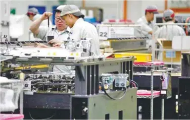  ?? – REUTERSPIX ?? Employees at work in a circuit board assembly factory. Some firms said their operating rates have risen to clear backlogs which had accumulate­d during factory closures.