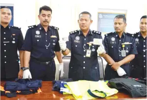  ??  ?? AZHAR menunjukka­n kad kuasa dan baju polis yang dirampas daripada suspek.