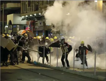  ??  ?? In this July 21 photo, protesters react to teargas as they confront riot police officers in Hong Kong. Hong Kong, a former British colony, was returned to China in 1997 under a “one country, two systems” concept that gives the city a fair degree of autonomy over its affairs, but China may intervene to quell protests now in their seventh week. AP PHOTO/VINCENT YU