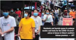  ?? ?? Residents and tourists queue to undergo nucleic acid tests for the COVID-19 coronaviru­s in Sanya in China’s southern
Hainan province. — AFP