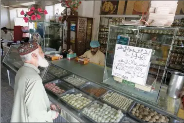  ?? ?? A man buys sweets Oct. 26 at a famous 67-year-old sweet shop run by a Hindu businessma­n in Shikarpur, Pakistan.