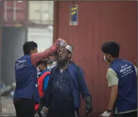  ?? (AP) ?? A rescuer pours water on the face of another on Sunday after a fire broke out at the BM Inland Container Depot in Chittagong, Bangladesh. More photos at arkansason­line.com/66bminland/.