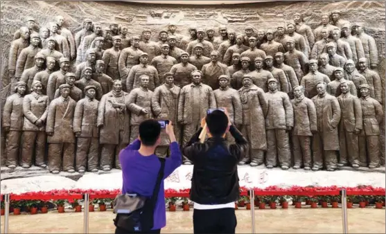  ?? WANG ZHUANGFEI / CHINA DAILY ?? Visitors take pictures of a grand relief featuring revolution­ary figures at the memorial hall in Xibaipo, Hebei province.