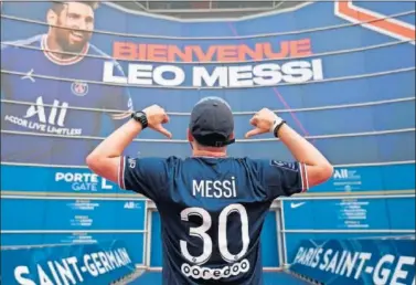  ??  ?? Un aficionado del PSG ante un cartel que da la bienvenida a Messi al fútbol francés.
