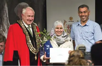  ?? Photo: Kevin Farmer ?? MIGRANTS: Toowoomba Regional Council Mayor Paul Antonio on stage with new citizen Fatimah Alzeyadi and her husband Majid Muttashar at an Australian Citizenshi­p Ceremony last year.