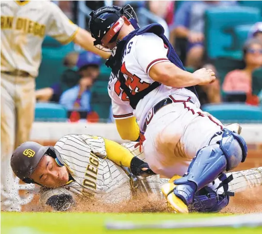  ?? TODD KIRKLAND GETTY IMAGES ?? Padres’ Ha-Seong Kim beats the tag of Braves catcher William Contreras to score in the 11th inning at Truist Park on Sunday. Earlier, Kim drove in the go-ahead run.