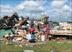  ?? AP/JEFFREY COLLINS ?? Friends and neighbors search the remains of a trailer Friday at the Boardwalk RV Park in Emerald Isle, N.C. A tornado from the outer band of Hurricane Dorian damaged about a dozen RVs nearly a day before Dorian’s eye passed just offshore of the island.